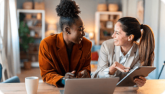 Duas profissionais conversando em uma reunião de trabalho
